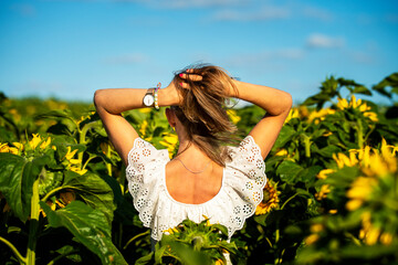 Fototapeta Dziewczyna dotykająca swoich włosów w polu słoneczników. Radość i przyjemność z kontaktu z przyrodą. obraz