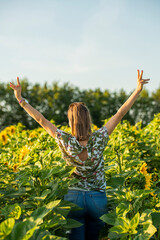 Kobieta stojąca w polu słoneczników. Osoba pokazująca palcami znak wolności. Dziewczyna z otwartymi ramionami.
