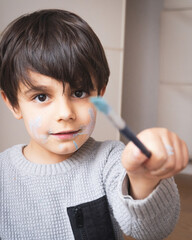 boy with face smeared with paint showing stain brushed with paint