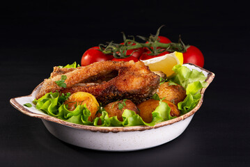 fried fish and baked potatoes on a dark background