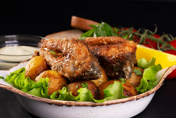 fried fish and baked potatoes on a dark background