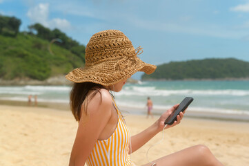 Fototapeta premium Young Beautiful woman in Bikini listening to music and using smartphone on the beach, Summer, vacation, holidays, Lifestyles concept.