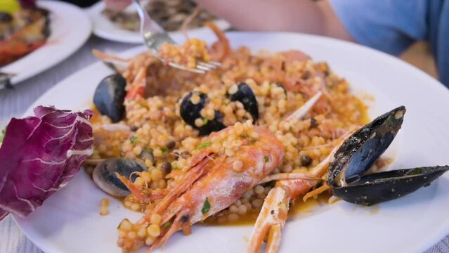 Italian pasta. Fregula with seafood. Traditional small round Sardinian pasta with shellfish, langoustine, mussels and vongole. in a restaurant. High quality FullHD footage
