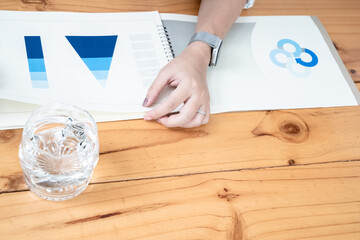 Employees Meeting in conference room. There are triangular diagrams, graphs, and related data set aside on a long brown wooden table.