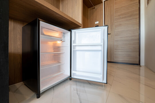 Opened Small Refrigerator Under The Wood Counter And In Front Of Enter Door Delux Room At Resort And Hotel.