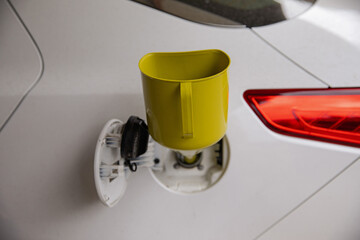 A can for pouring gasoline from the canister into the car. Yellow watering can in the fuel hole. Gasoline collapse. Alternative method of filling the car