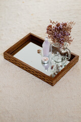 Dried flowers vase, soap, skin care products and candle on mirror tray. Aesthetic minimalist composition.
