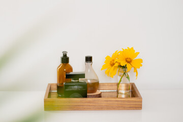 Perfume, wildflower vase, lotion and liquid soap on mirror tray. Aesthetic minimalist bathroom composition.