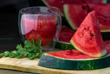 Delicious watermelon  outdoors wooden  table, GREEN  natural background sunny day, Heap,  Fresh ripe red, leaf, summer sunny garden juice drink organic sweet fruit, vegan food Tasty sliced board plate