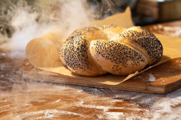 Bun with poppy seeds on parchment. Smoke. Smoke from baking. Fresh bakery. Baking for breakfast