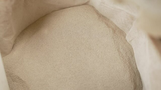 Construction dry mix in a bag. Open paper bag with dry mortar for construction work. Sand for laying paving stones in a bag.