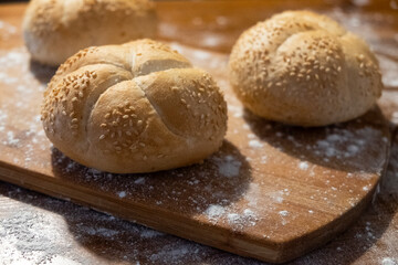 small buns with sesame seeds on a board sprinkled with flour. Fresh bakery. Food breakfast. Sandwich buns