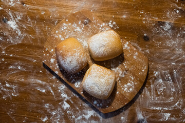 buns sprinkled with flour on a wooden board. Buns on the table. Bakery products.