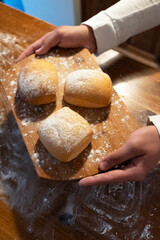 Buns on a wooden board. A man holds cooked buns. Baking for breakfast. Bakery products