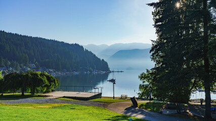Scenic view of early summer morning mist over mountains bordering sea inlet at Deep Cove, BC, a popular destination with kayakers and boaters of all descriptions.