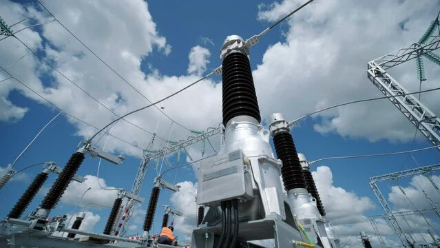 Motion past glass insulators on supports and cable bus pipes in switchyard of contemporary substation under clear blue sky