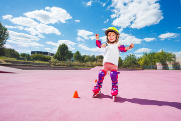 Little girl in helmet and protection learn to skate on rollers