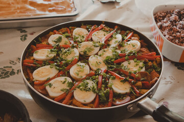 big pan with pork paella and eggs on the top