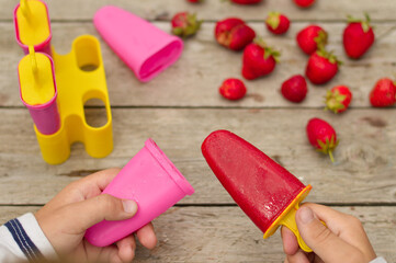 Selective focus of a hand holding homemade strawberry ice cream.
