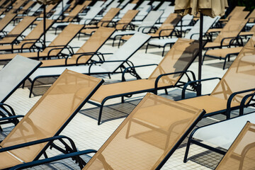 Close-up of rows of sun loungers by a swimming pool