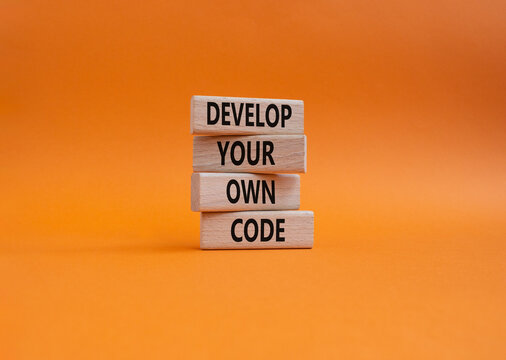 Develop your own code symbol. Concept words Develop your own code on wooden blocks. Beautiful orange background. Business and Develop your own code concept. Copy space.
