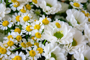 white bouquet of daisies and chrysanthemums wrapped in newsprint in a vase, crop