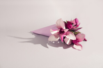A bouquet of magnolia flowers in a pink paper fisque against a white background. Spring minimal concept.