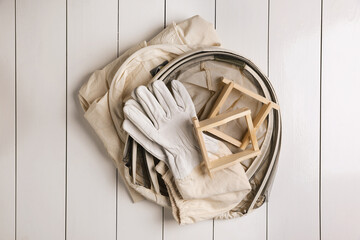 Honeycomb frames and beekeeping tools on white wooden table, flat lay