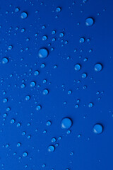 Water drops on blue background, top view