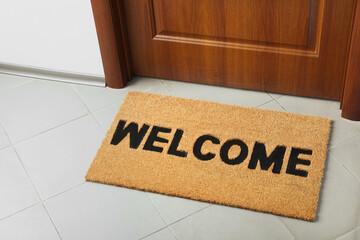 Door mat with word Welcome on floor near entrance, above view
