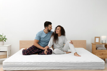 Happy couple on bed with comfortable mattress at home