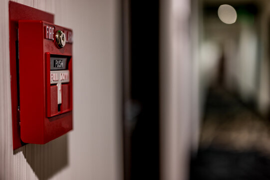 Selective focus on a wall mounted fire alarm switch in a empty hallway