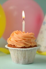 Tasty birthday cupcake with candle on light blue table, closeup