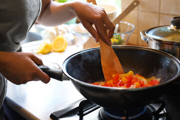 Woman cooking vegetables in frying pan indoors, closeup