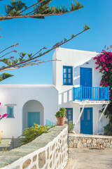 Fototapeta premium Typical Cycladic architecture, Greek whitewashed house with blue windows and summer flowers in Folegandros Island. Greece