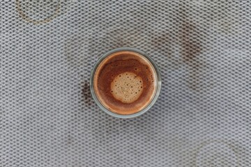 Top view of black coffee with beautiful crema on dirty grey cloth.