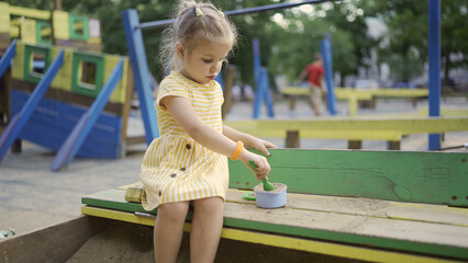 Cute little girl is playing in the sandbox on the playground. Child girl playing on the playground...