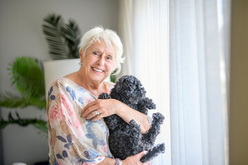 cute senior woman with poodle on the living room