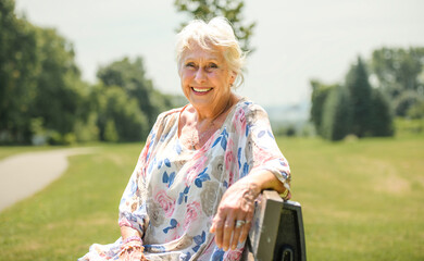 Portrait of senior woman outside in nature sit on a parc bench