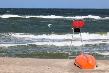 Czerwona flaga na plaży oznacza zakaz kąpieli bo sztorm - obrazy, fototapety, plakaty