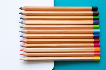 Fototapeta premium wooden colored pencils on blank page of a notebook