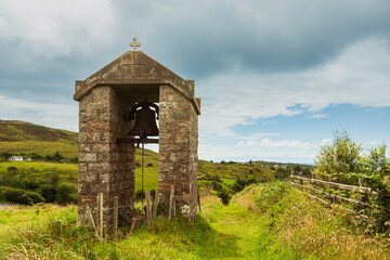 The old bell tower of the church on a picturesque field on a clear day.