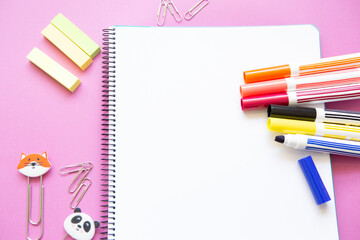 different colored felt-tip pens and other stationery on blank page of notebook