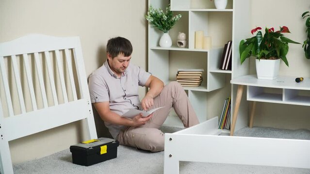 The man studies the instructions for assembling a children's bed