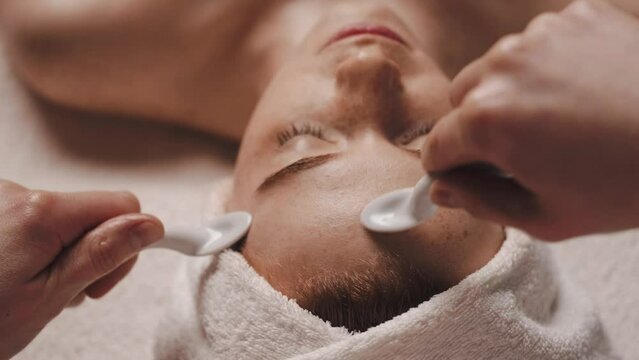 Beautician massaging woman's face with uno spoons. Cosmetic beauty spa salon. Skin care. Medical treatment.