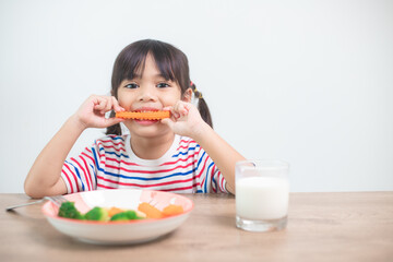 Cute asian child girl eating healthy vegetables and milk for her meal