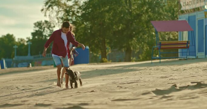 Children run along the beach with a dog. Boy and a girl walk with a puppy along the riverbank. Happy childhood, a walk with a pet. 4k, ProRes