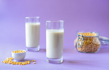 Vegan healthy pea milk in two glasses, pea seeds. Lilac background. Copy space