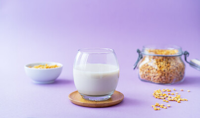 Vegan healthy pea milk in glass, pea seeds. Lilac background. Copy space