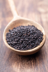 Bio natural black sesame seeds on wooden spoon.